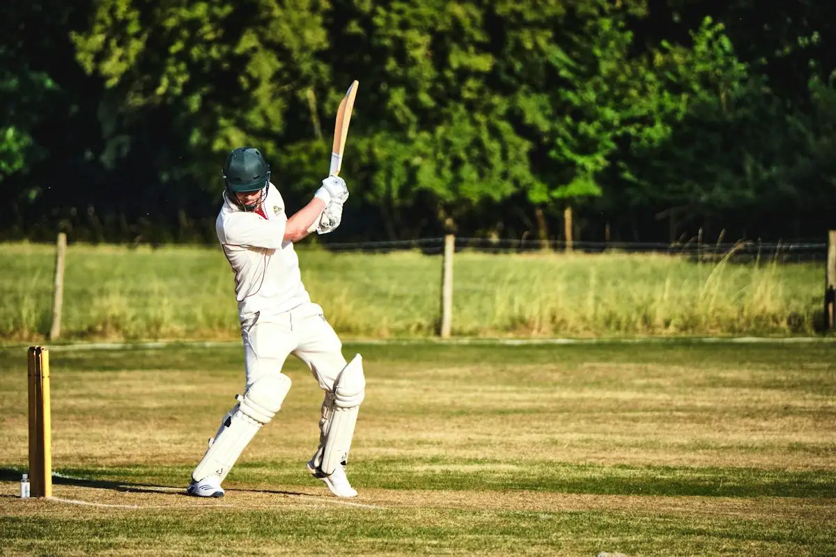 Batter following through on a shot on a green outfield
