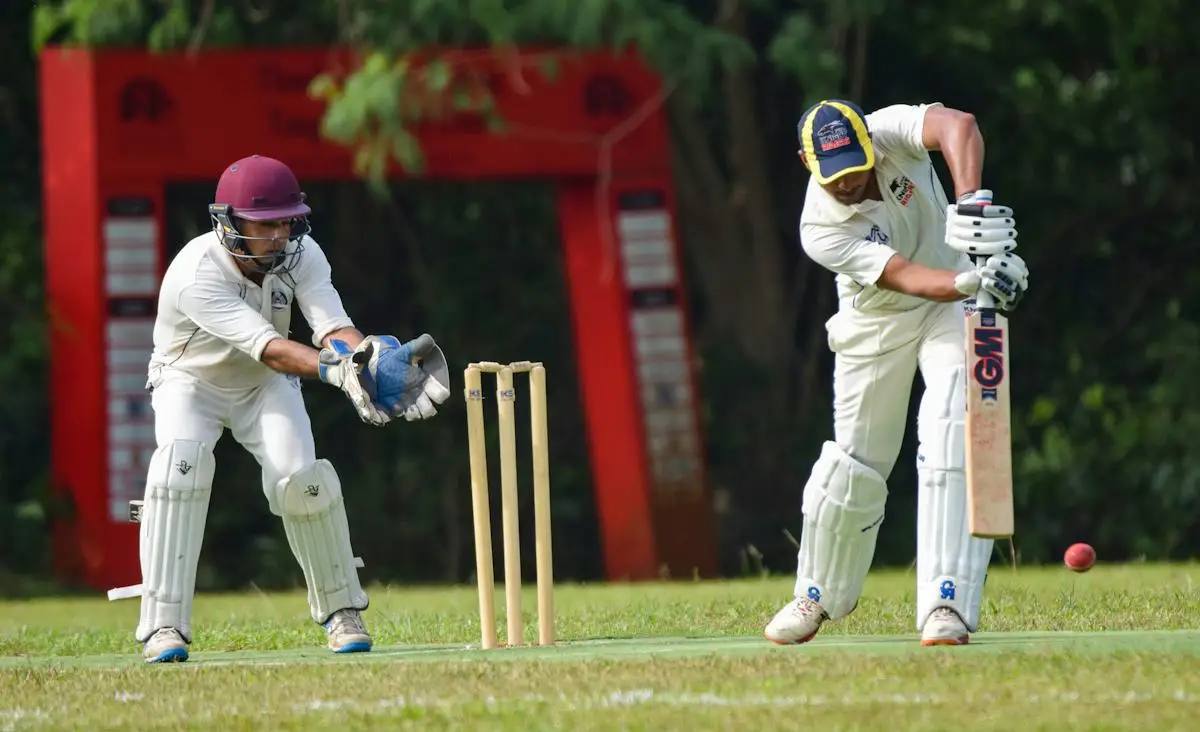 Batter and wicketkeeper taking position beside cricket stumps