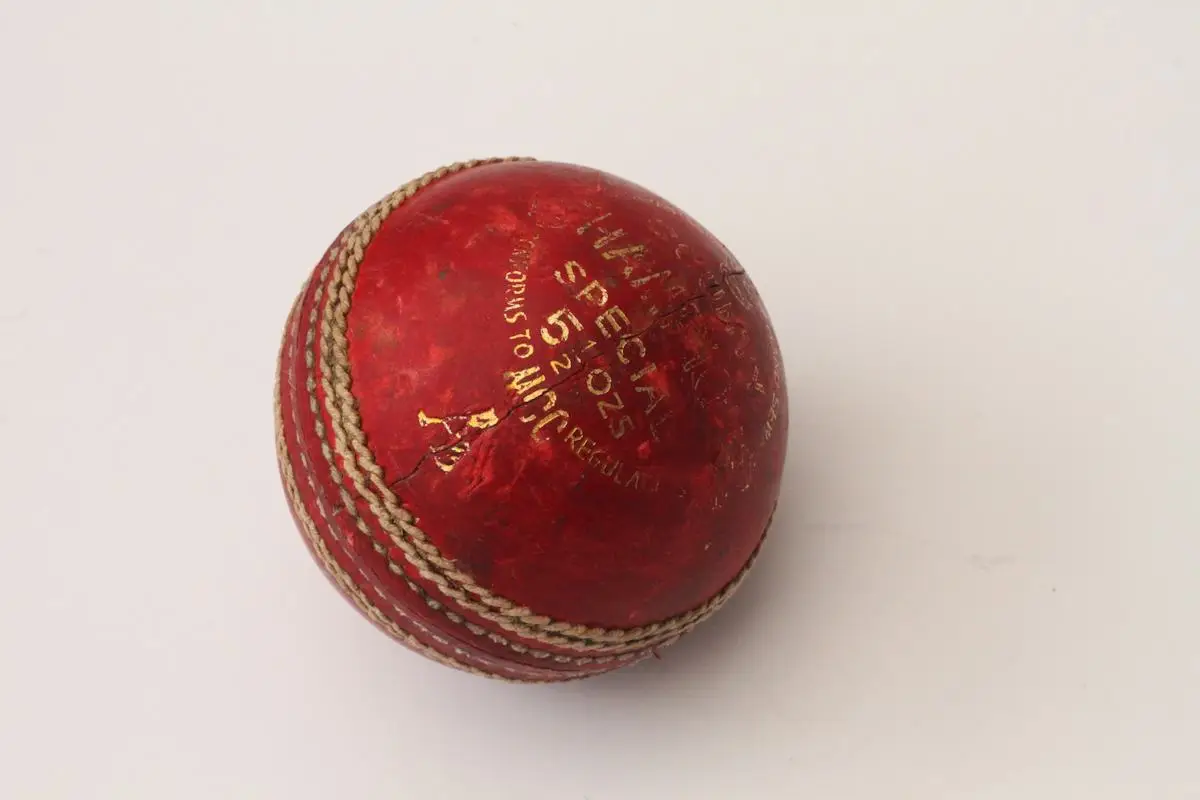 Red leather cricket ball with a raised stitched seam