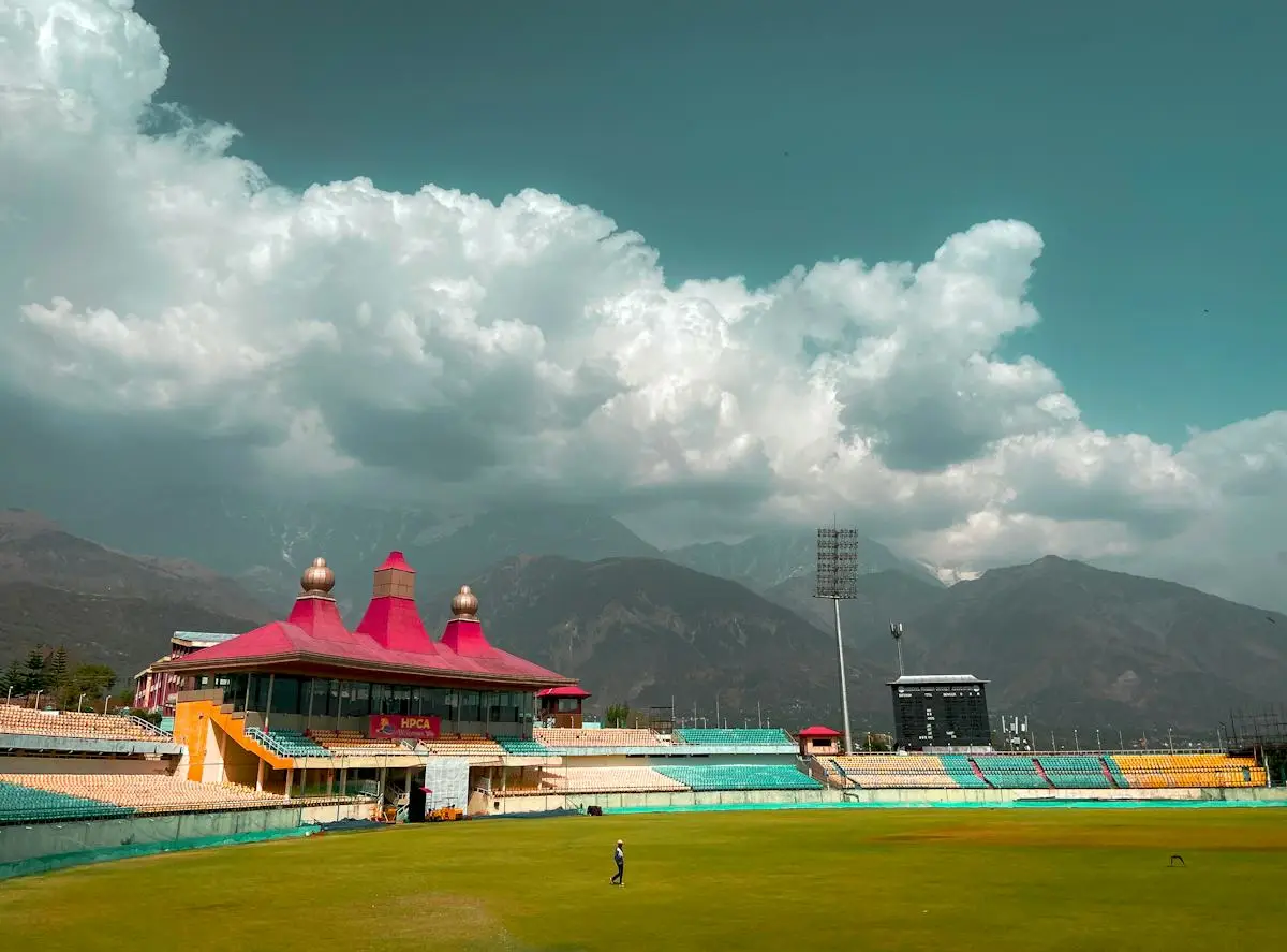 Cricket ground with a red-roofed pavilion and distant mountains