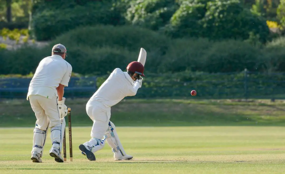 Batter playing a shot with a wicketkeeper behind the stumps