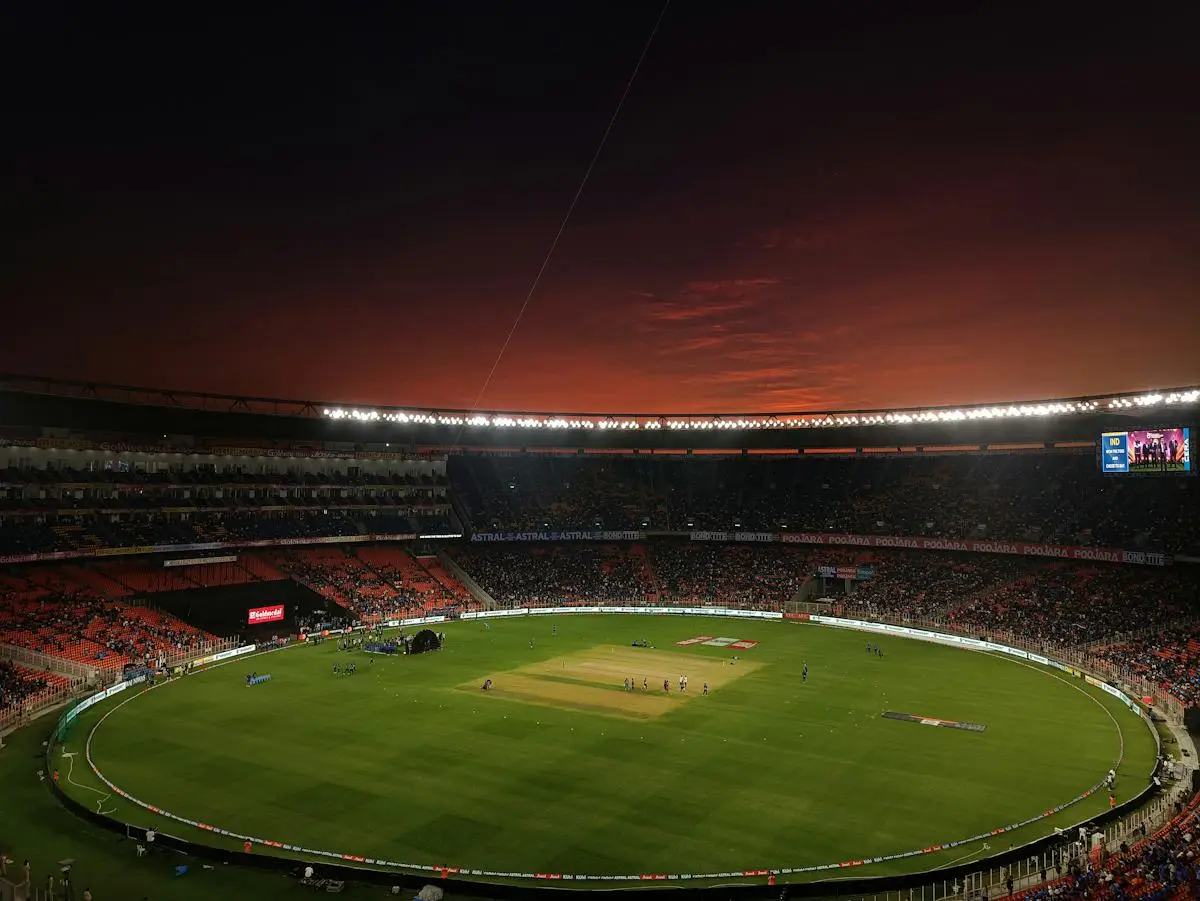 Wide cricket ground beneath a sunset sky